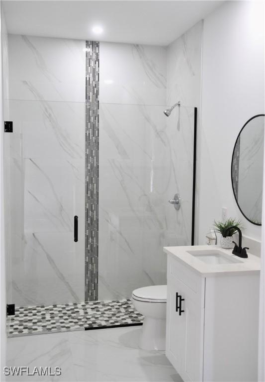 full bathroom with toilet, marble finish floor, a marble finish shower, and vanity