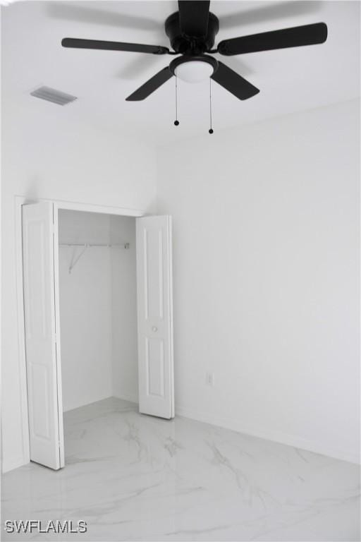 unfurnished bedroom with ceiling fan, marble finish floor, a closet, and visible vents