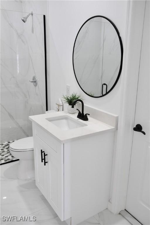 full bath with toilet, marble finish floor, a marble finish shower, and vanity