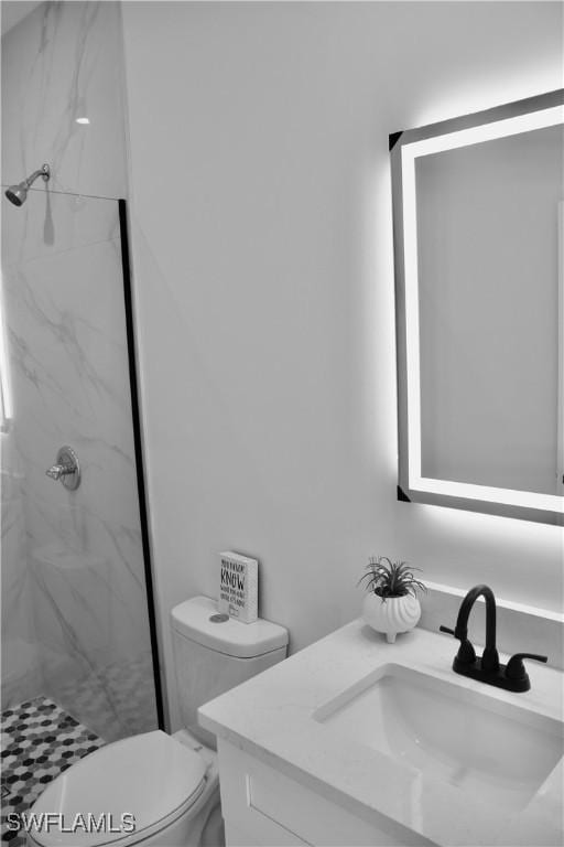 bathroom with toilet, a marble finish shower, and vanity