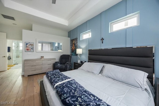 bedroom with hardwood / wood-style flooring and ensuite bath