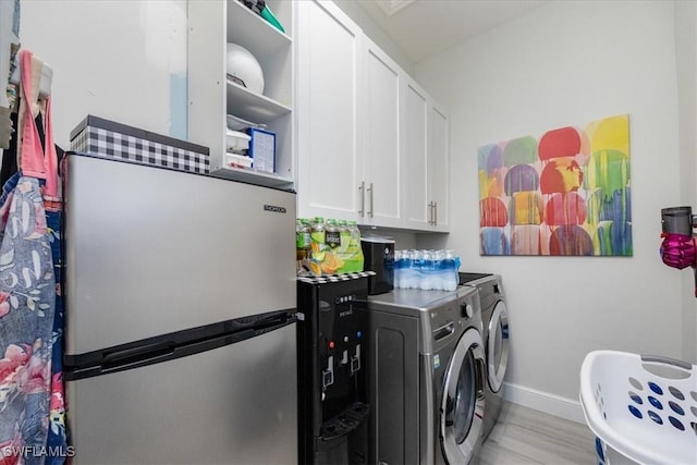 washroom featuring cabinets, separate washer and dryer, and light hardwood / wood-style floors