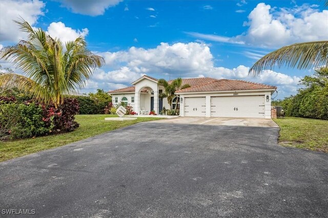 mediterranean / spanish house featuring a garage and a front lawn