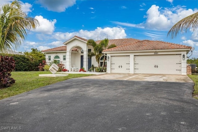 mediterranean / spanish-style home with a garage and a front lawn