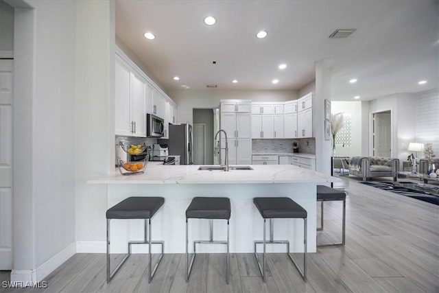 kitchen with white cabinetry, sink, a kitchen bar, and appliances with stainless steel finishes