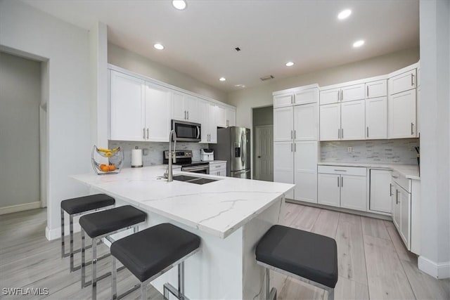 kitchen with white cabinetry, appliances with stainless steel finishes, a kitchen bar, and kitchen peninsula