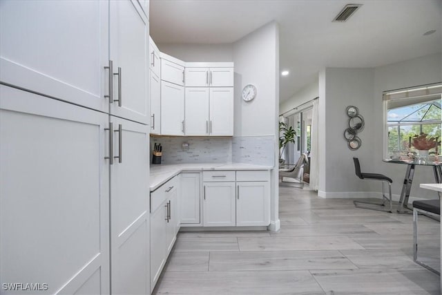 kitchen featuring white cabinets, light hardwood / wood-style floors, and decorative backsplash