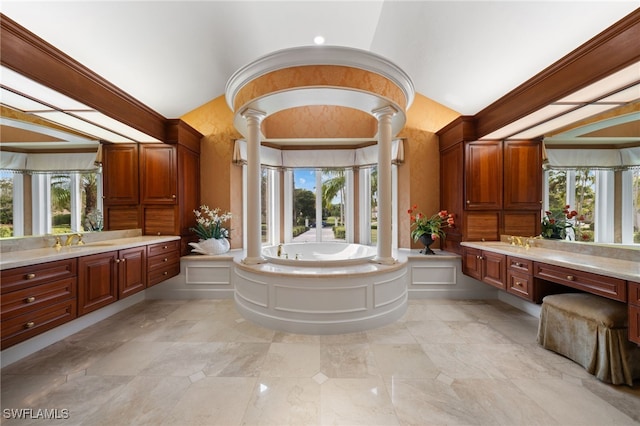 bathroom with a bathing tub, vanity, ornate columns, and a healthy amount of sunlight