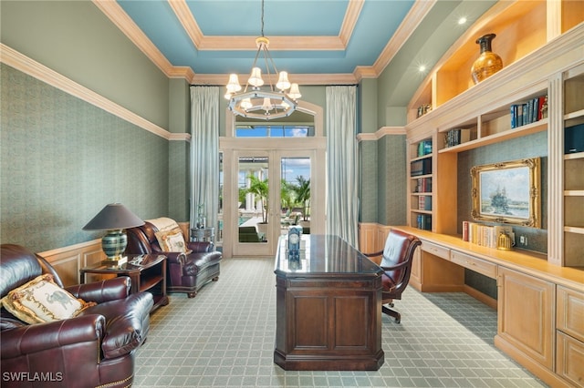 carpeted home office with an inviting chandelier, french doors, a raised ceiling, crown molding, and built in desk