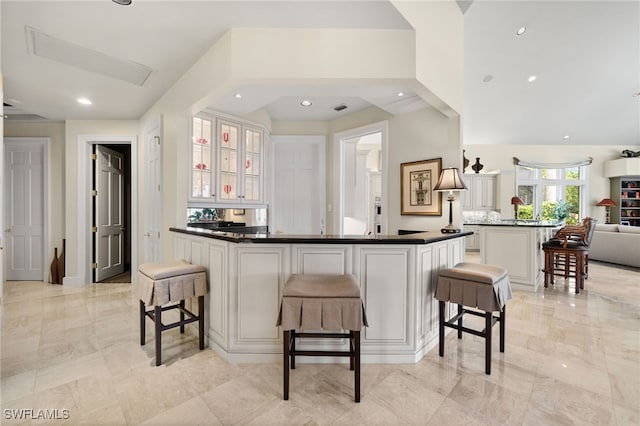 kitchen with white cabinets, a kitchen island, a kitchen bar, and kitchen peninsula