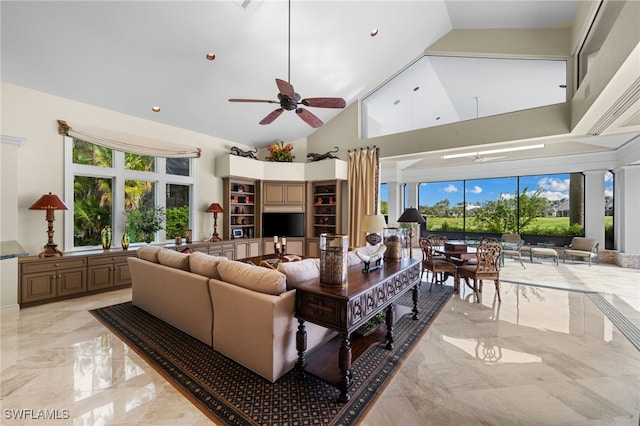 living room featuring ceiling fan, a towering ceiling, and a wealth of natural light