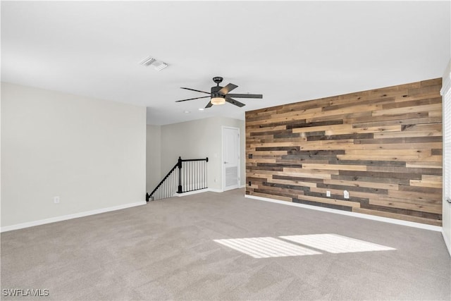 spare room with wood walls, carpet, and ceiling fan