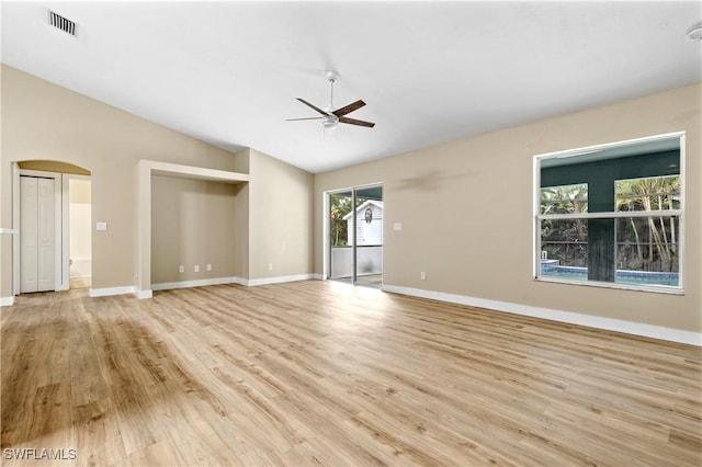 unfurnished room featuring baseboards, lofted ceiling, arched walkways, ceiling fan, and light wood-style floors