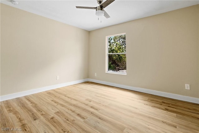 spare room featuring baseboards, ceiling fan, and light wood finished floors