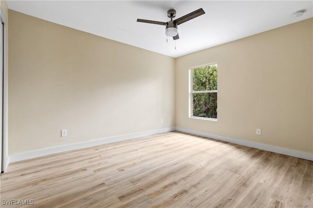 spare room with light wood-type flooring, baseboards, and a ceiling fan