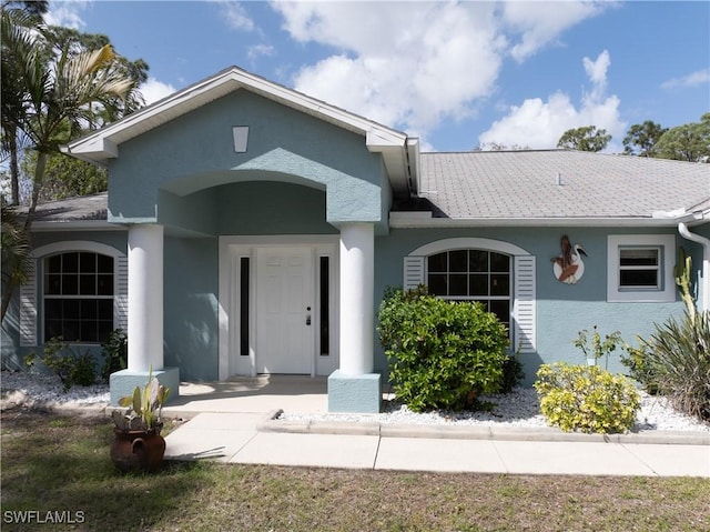 view of front of home featuring a shingled roof and stucco siding