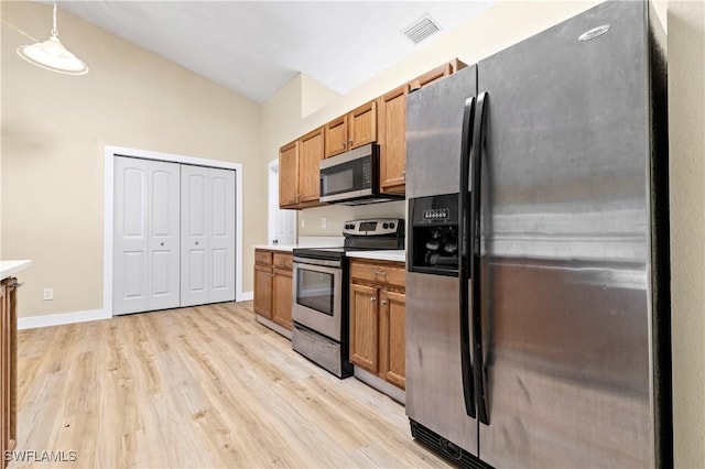 kitchen with visible vents, light wood-style flooring, stainless steel appliances, brown cabinetry, and light countertops