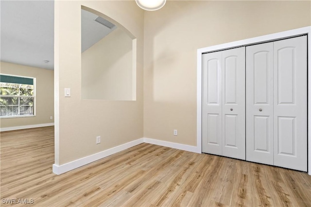 unfurnished bedroom with a closet, visible vents, baseboards, and wood finished floors