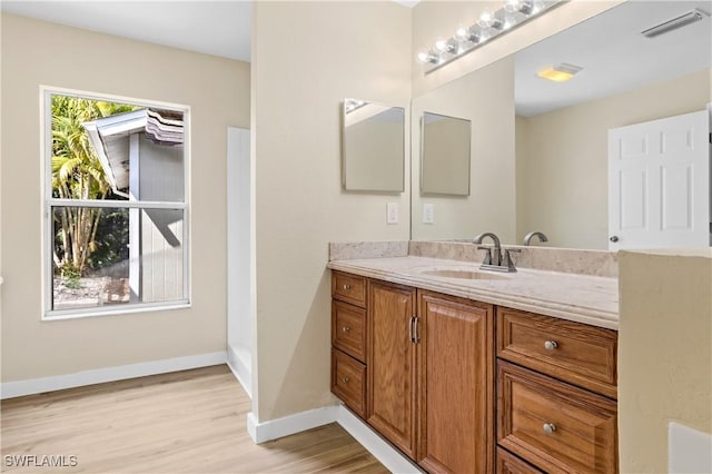 bathroom featuring visible vents, baseboards, wood finished floors, and vanity