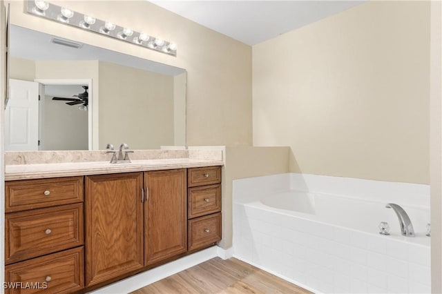 bathroom with visible vents, wood finished floors, a bath, vanity, and a ceiling fan