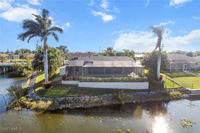 rear view of property featuring glass enclosure, a yard, and a water view