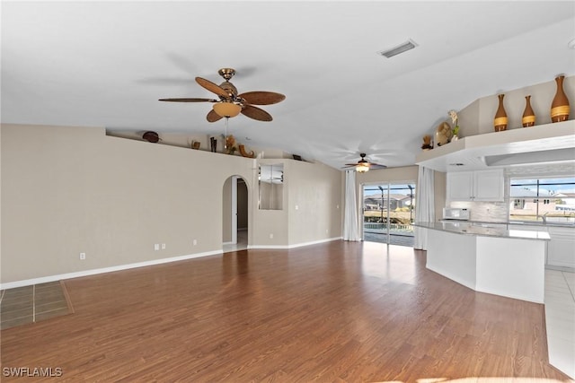 unfurnished living room with ceiling fan, light hardwood / wood-style floors, and lofted ceiling