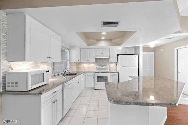 kitchen featuring stone counters, white appliances, a tray ceiling, and white cabinetry