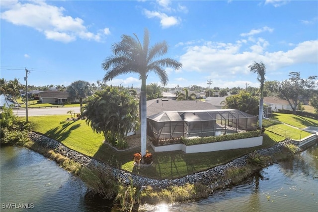 back of house with a yard, a water view, and a lanai