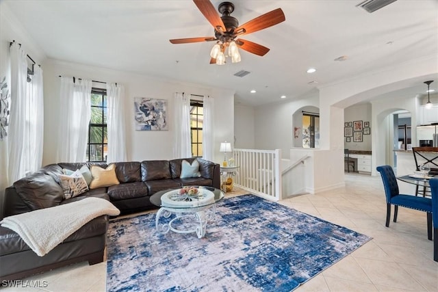 living room with light tile patterned floors, ceiling fan, and crown molding