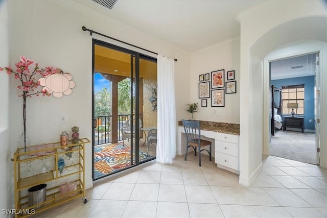 entryway featuring crown molding, light tile patterned floors, and built in desk