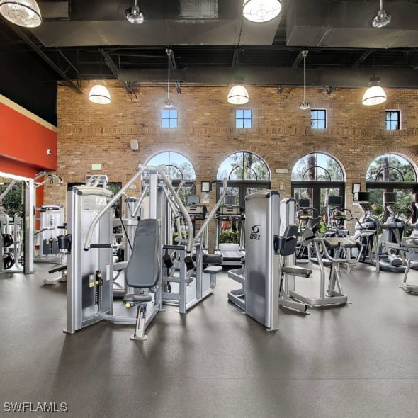 workout area with a high ceiling and brick wall