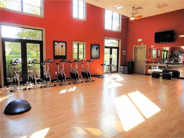 exercise room featuring ceiling fan, light hardwood / wood-style floors, and a high ceiling