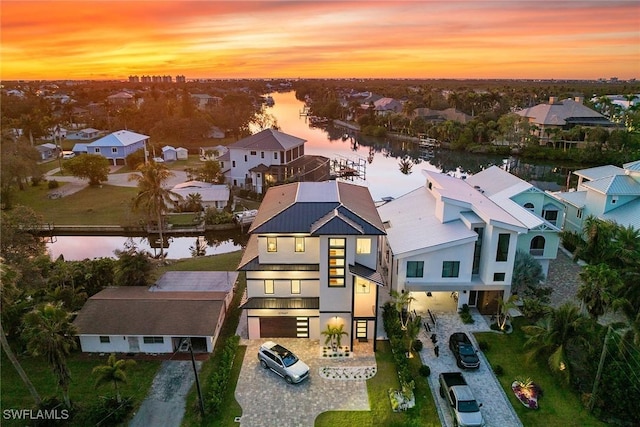 aerial view at dusk featuring a water view and a residential view