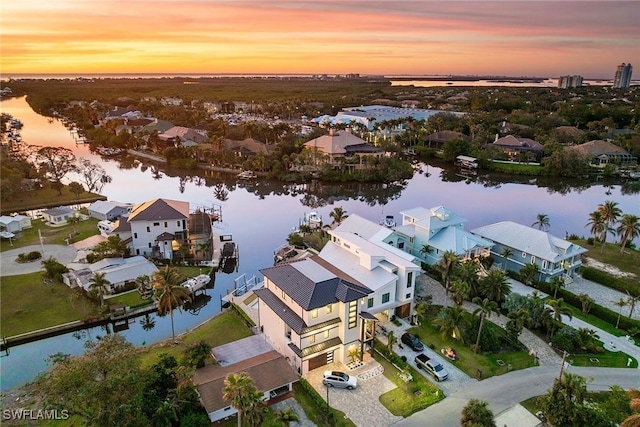 aerial view at dusk with a water view and a residential view