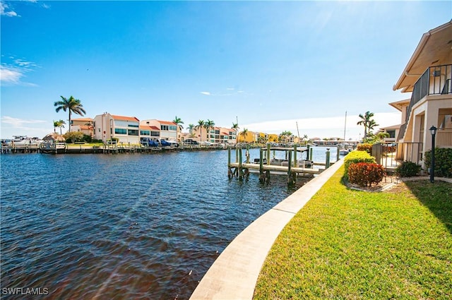 dock area with boat lift, a yard, and a water view