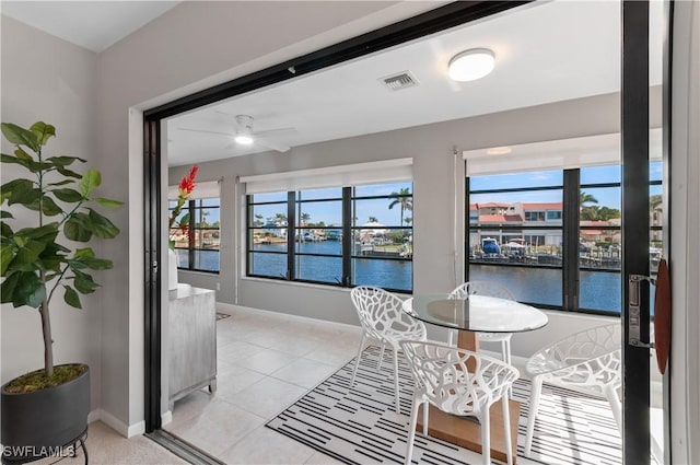 dining area featuring visible vents, a healthy amount of sunlight, baseboards, and a water view