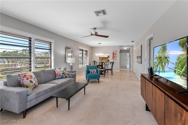 living area featuring light carpet, visible vents, and a ceiling fan