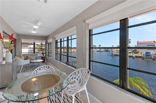 sunroom / solarium featuring ceiling fan and a water view