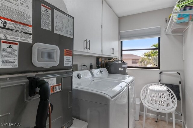 clothes washing area with light tile patterned floors, cabinet space, and washer and clothes dryer