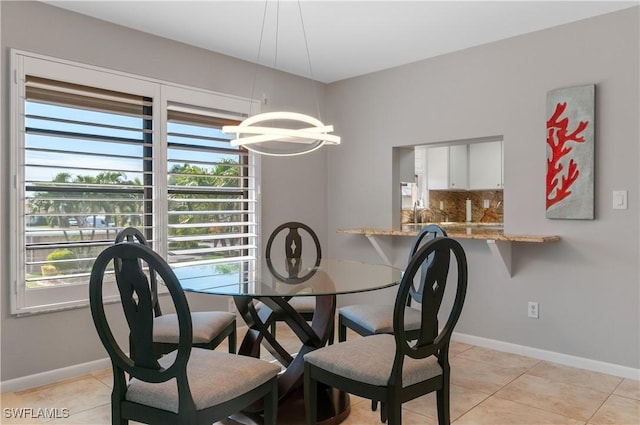 dining space featuring a notable chandelier, light tile patterned flooring, and baseboards