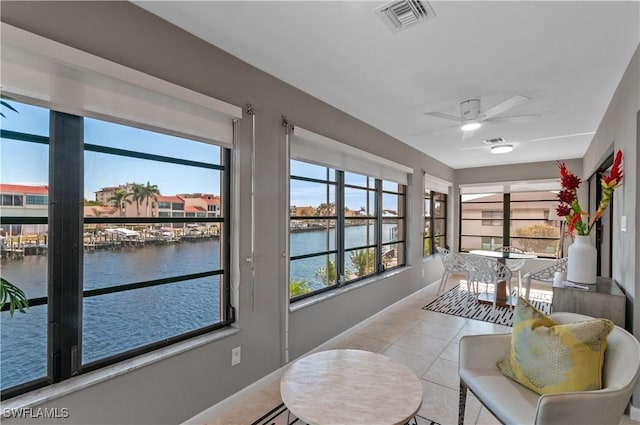 sunroom featuring a water view and ceiling fan