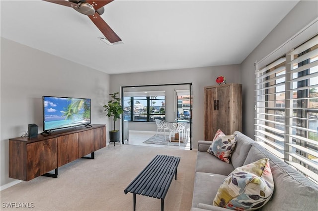 living room with a ceiling fan, light colored carpet, and visible vents