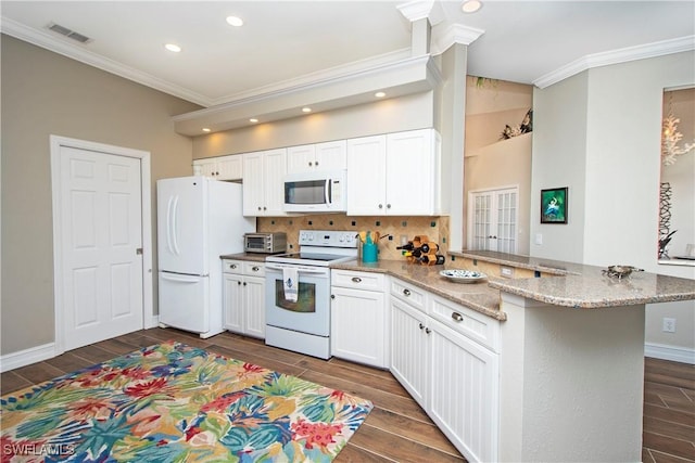 kitchen with kitchen peninsula, decorative backsplash, light stone counters, white appliances, and white cabinets