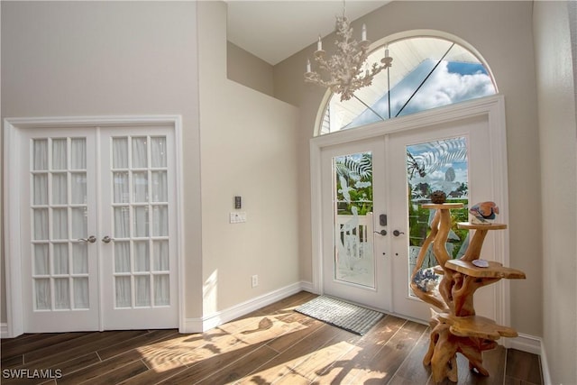 entryway with dark hardwood / wood-style floors, an inviting chandelier, and french doors