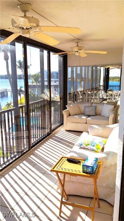 sunroom / solarium featuring ceiling fan and a water view