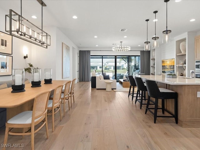 dining space featuring built in shelves, sink, and light hardwood / wood-style floors