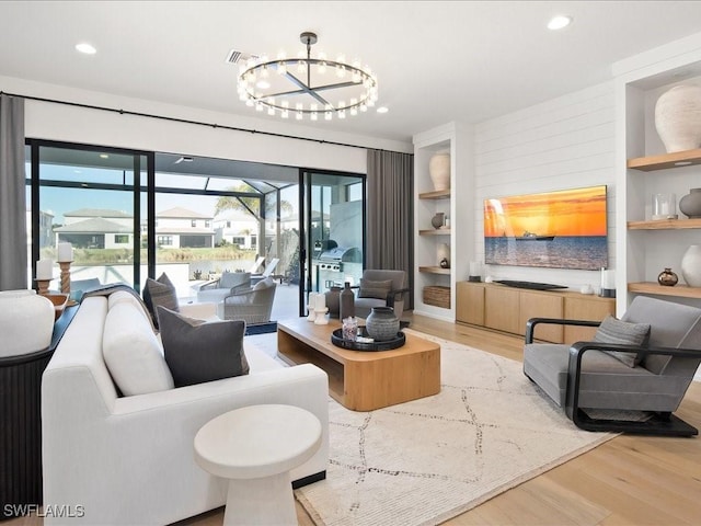 living room with built in shelves, a notable chandelier, and wood-type flooring