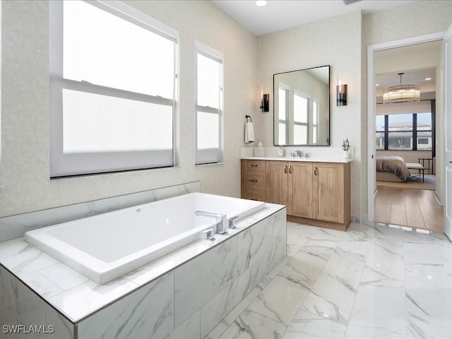 bathroom with vanity and tiled tub