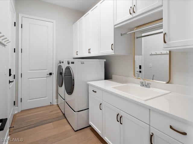 washroom featuring cabinets, light wood-type flooring, washing machine and clothes dryer, and sink