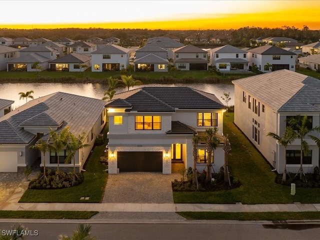 view of front facade with a lawn, a water view, and a garage